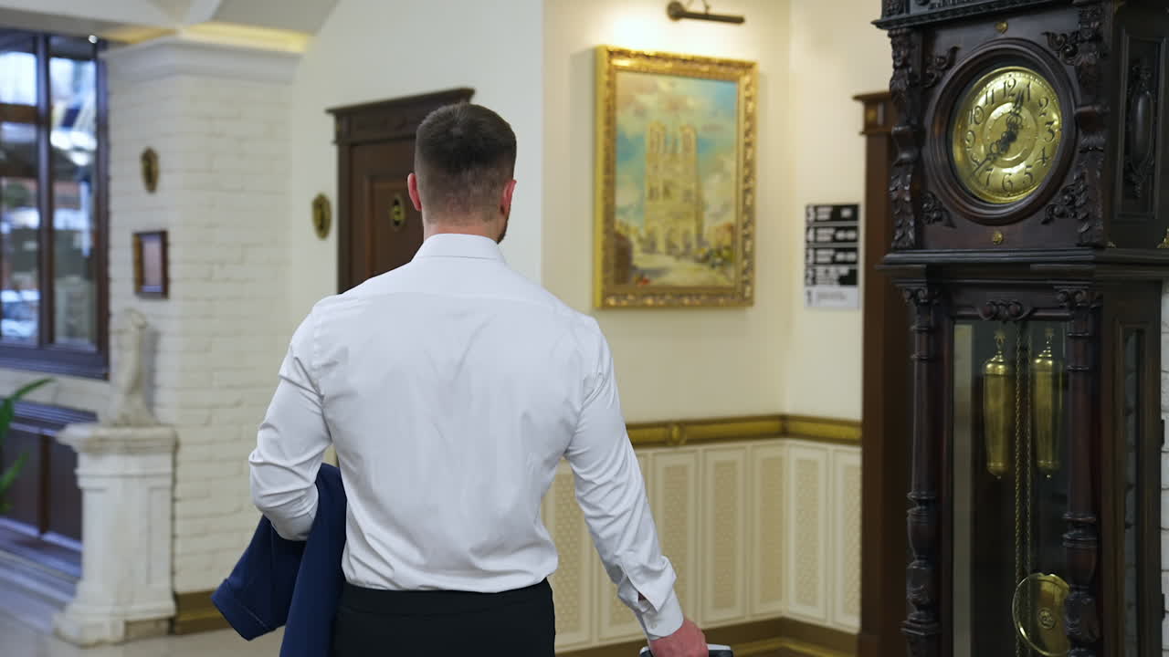 Businessman in luxury hotel. Back view of a man in white shirt walking to the lift in the hotel. Rear view. Business travel.