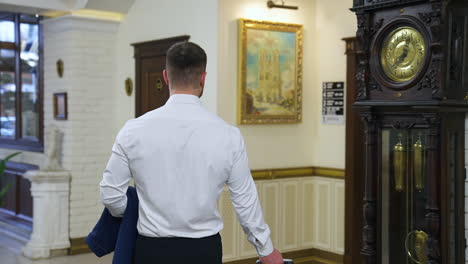 businessman in luxury hotel. back view of a man in white shirt walking to the lift in the hotel. rear view. business travel.