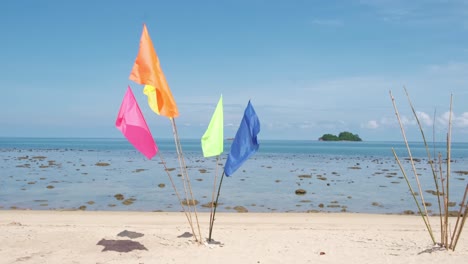 4k slowmotion static shot of colourful beach flags in tropical island in koh chang, thailand