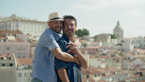 medium shot of cheerful gay man hugging his boyfriend from back with amazing landscape