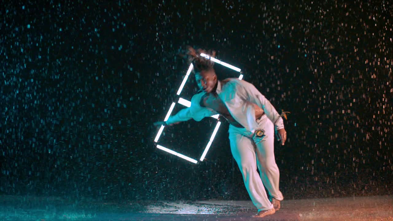 Capoeira dancer performing amazing spinning jump kick in the rain in super slow motion