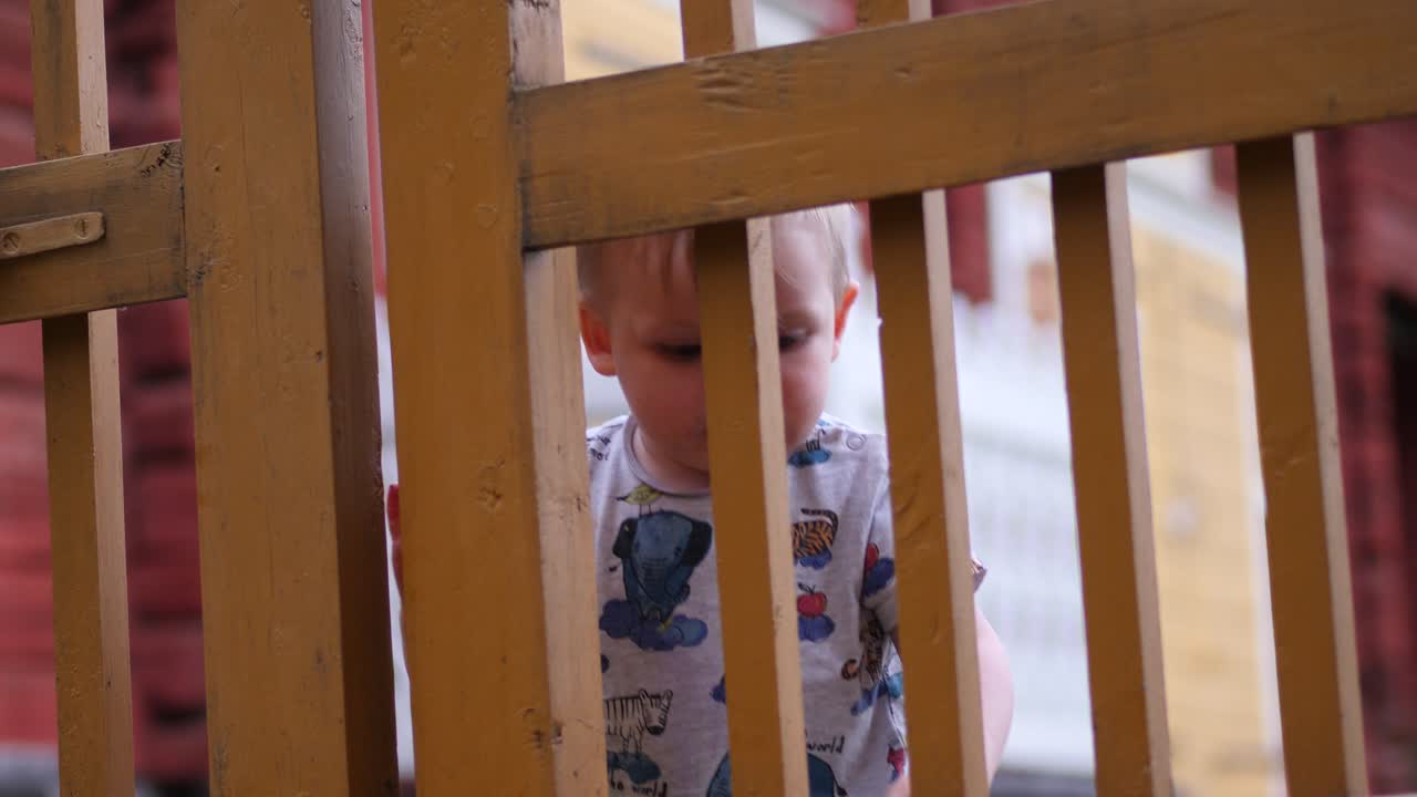Young kid at garden fence gate, childhood problem solving concept