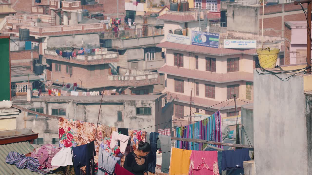 A Woman Hanging Clothes In The Cloth Line On The Roof Top On A Sunny Day In Kathmandu, Nepal-wide shot