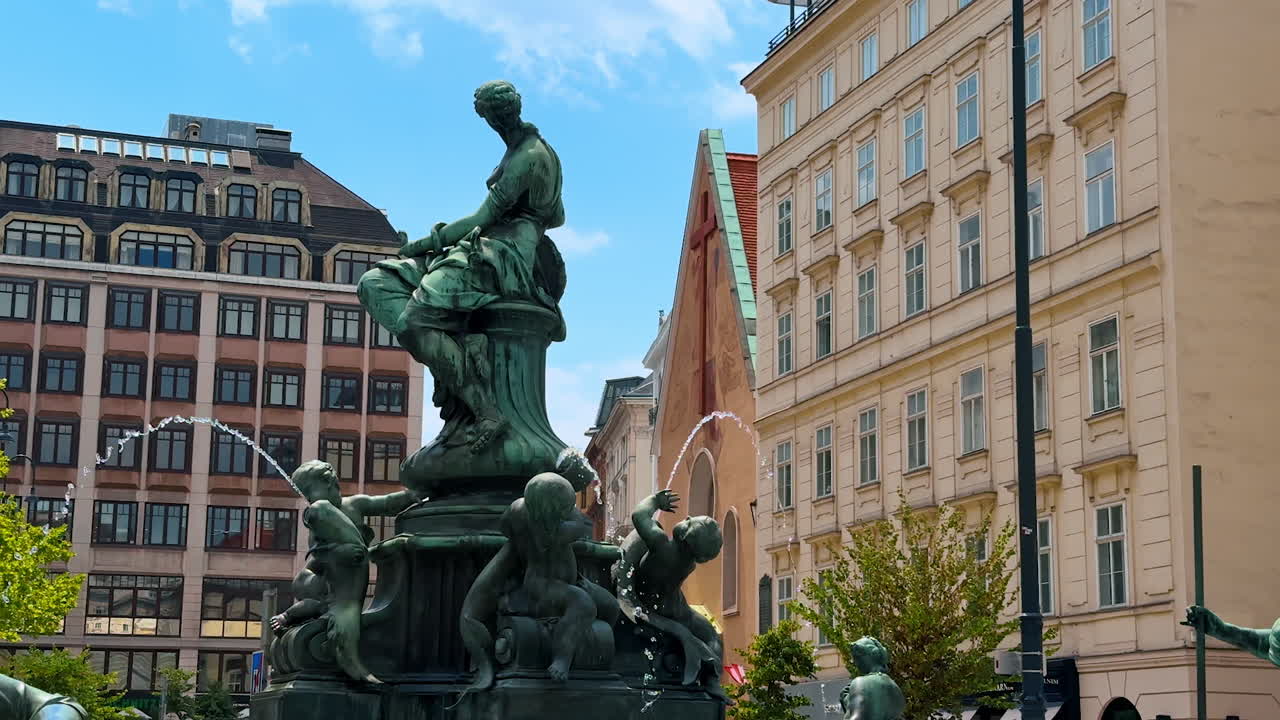 Vienna, Austria - June 9, 2025: Beautiful statues on the working fountain. Spectacular old style buildings at backdrop. Vienna, Austria