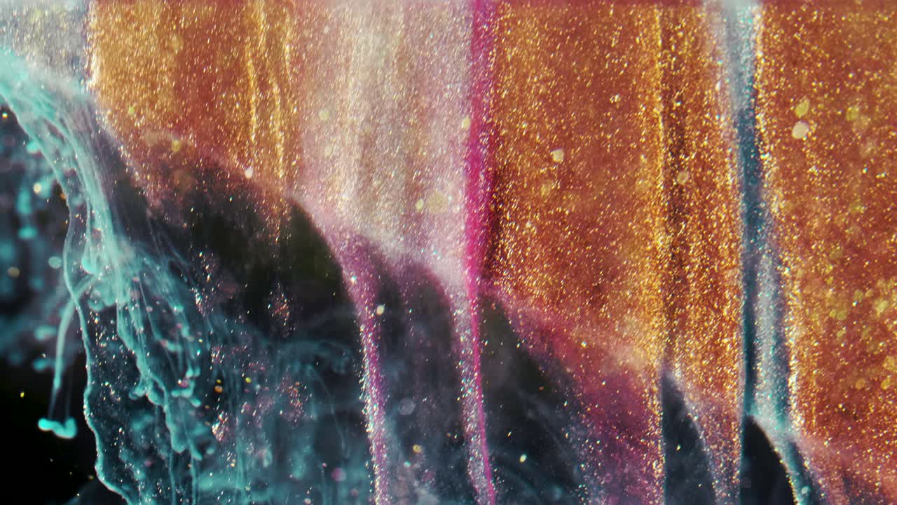 황금 잉크 입자는 검은 바탕에 다채로운 혼란으로 물에 흐른다.