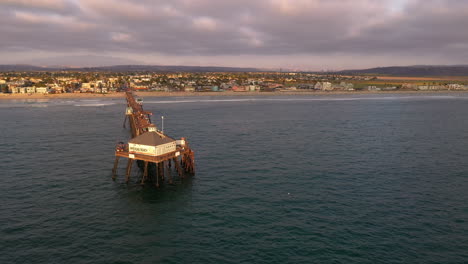 Dron-Sobre-El-Agua,-Orbitando-Lentamente-Alrededor-Del-Frente-Del-Muelle-De-La-Playa-Imperial