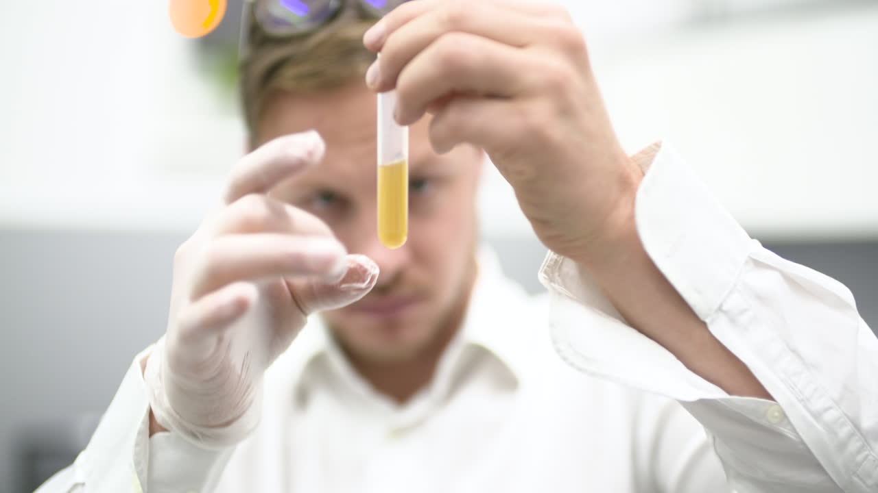 Scienziato che esamina liquido giallo in provetta in laboratorio