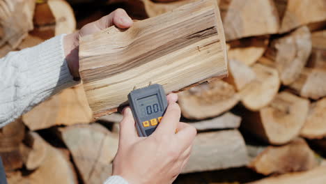 the owner of the fireplace checks the humidity of the firewood before kindling the fireplace