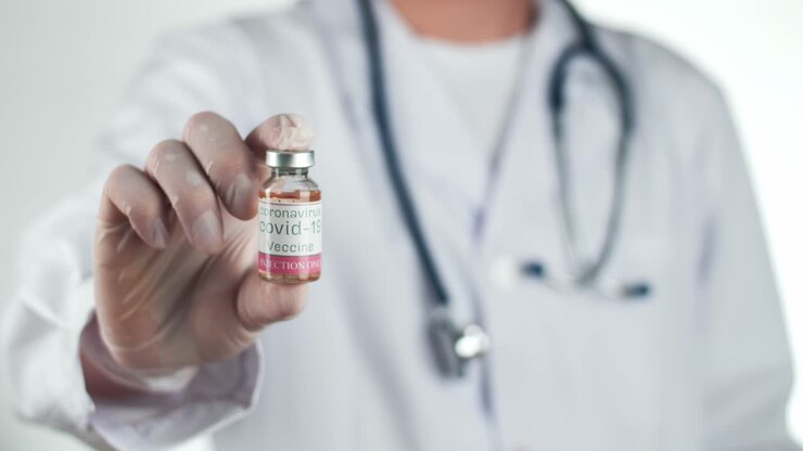 Medico che tiene il vaccino COVID-19