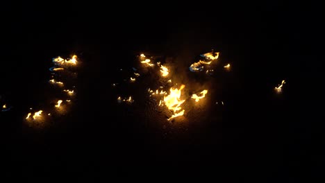 video de fuego y llamas. un pozo de fuego, gas o gasolina ardiente arde con fuego y llama. llamas y chispas ardientes de cerca, patrones de fuego. un resplandor infernal de fuego en la oscuridad. gasolina arde en el asfalto