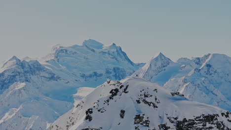 aerial footage of the iconic freeride paradise of verbier on a stunning bluebird day. snow-covered peaks, wide open faces, and legendary off-piste terrain under clear alpine skies
