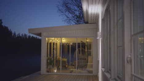 outdoor cozy glass room patio at night with illumination of lamps and decoration