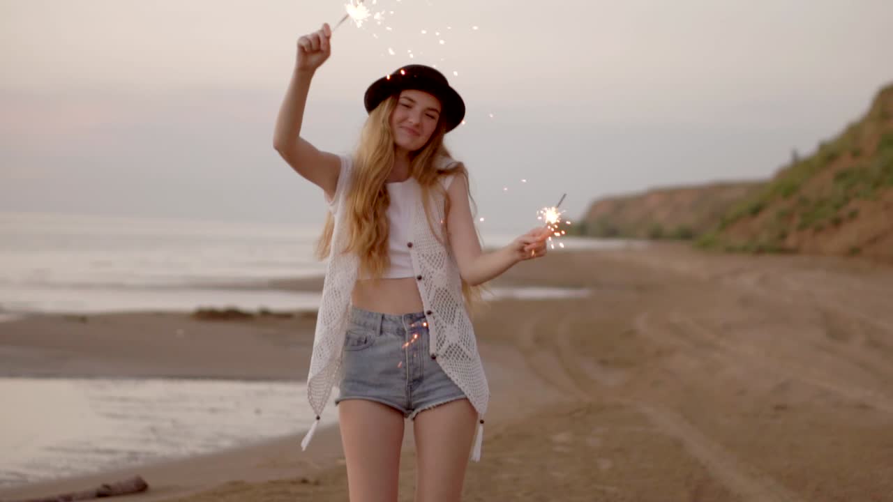 Happy Woman with Sparkler on Beach at Sunset