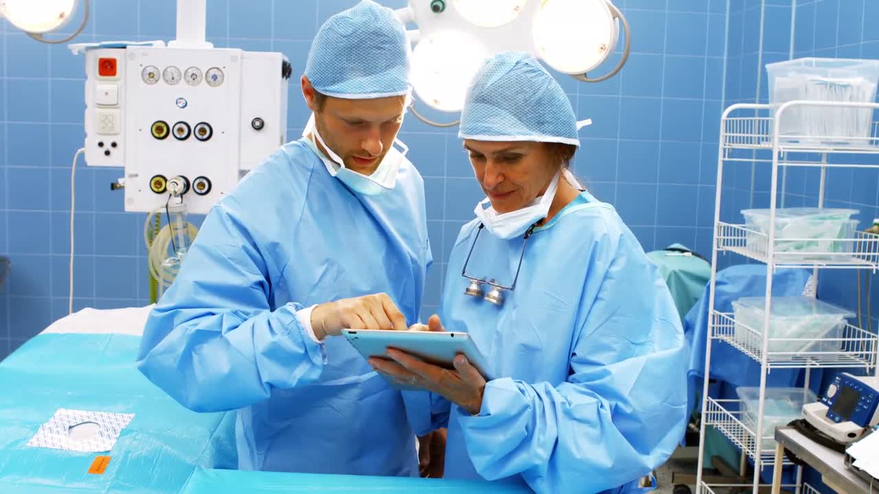 Cirujanos y cirujanas utilizando una tableta digital en quirófano