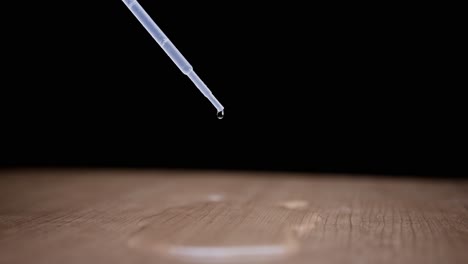 dripping water drop from a pipette, super slow motion on wooden surface