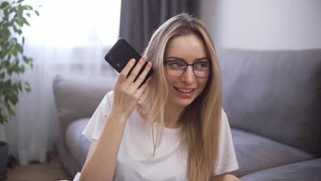 Blondes-Mädchen-Nutzt-Virtuellen-Assistenten-Auf-Dem-Mobiltelefon,-Hört-Audio-Nachrichten-Und-Lächelt