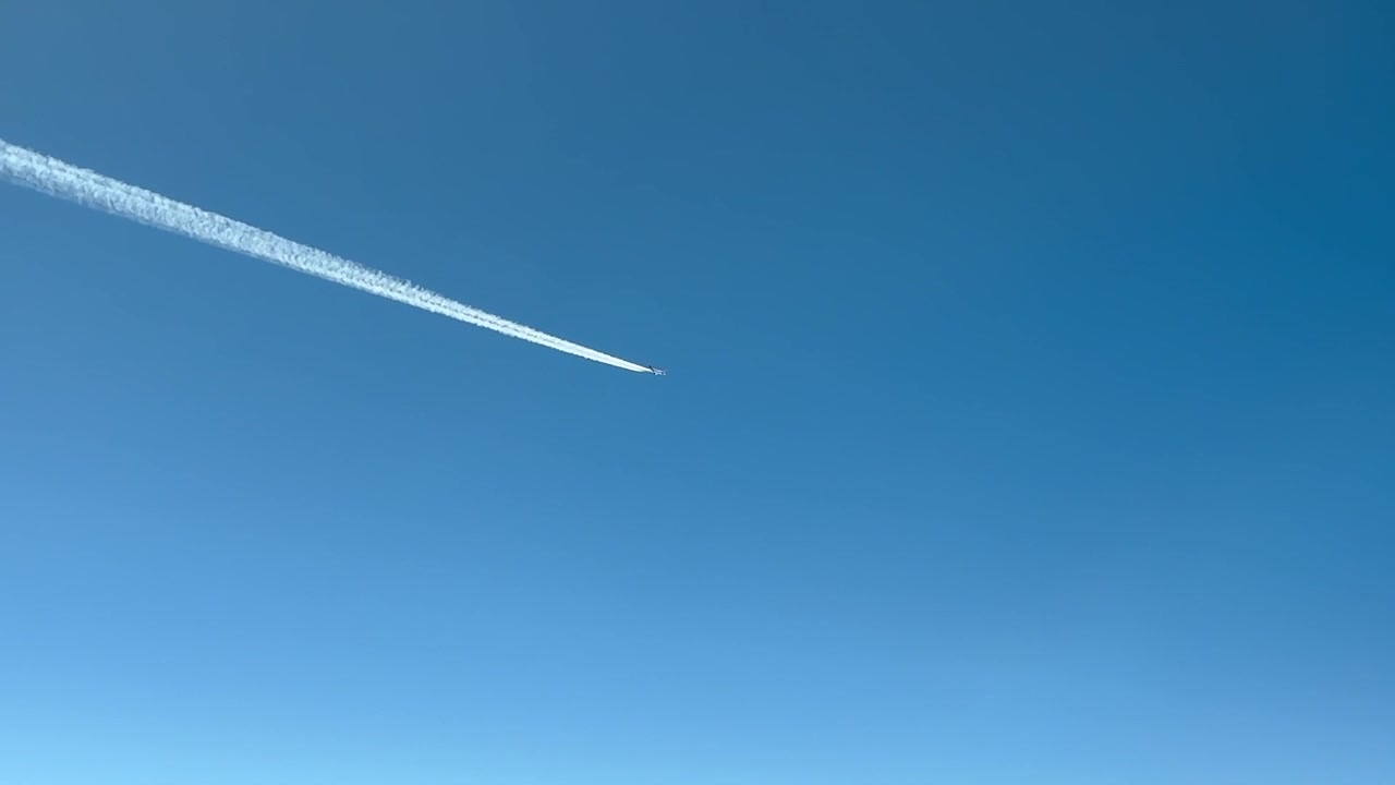 Vista dalla cabina di pilotaggio durante la crociera di un aereo a reazione e la sua scia di condensazione che svanisce in un cielo blu, attraversamento diagonale