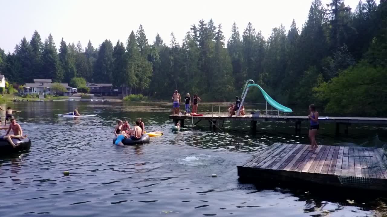 People enjoying the summertime while having fun with the cool waters of the mountain lake in Washington, USA - medium shot