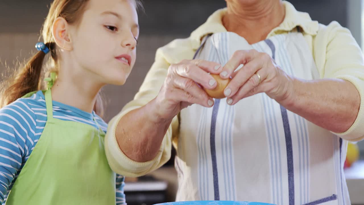 abuela rompiendo un huevo en un tazón y una niña pequeña viendo 4k 4k