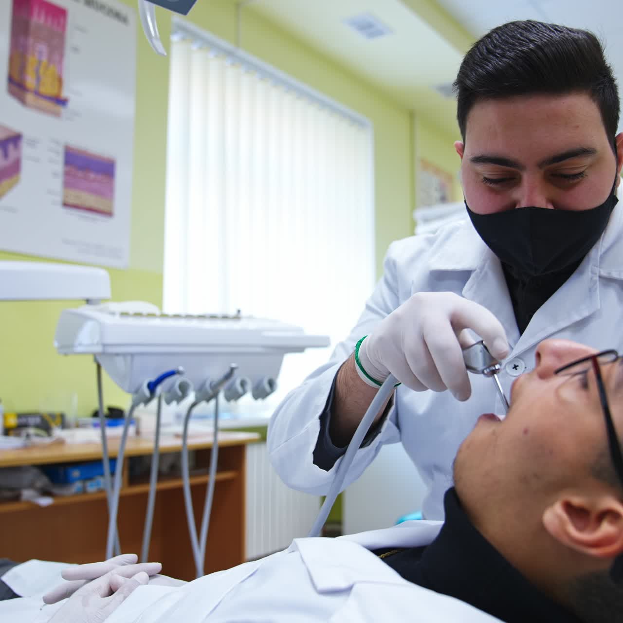Arab students practicing in dentistry. One male student applies electric dental tool to another one. Close up