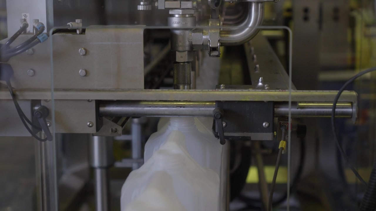 Automated machine fills plastic coolant containers on production line