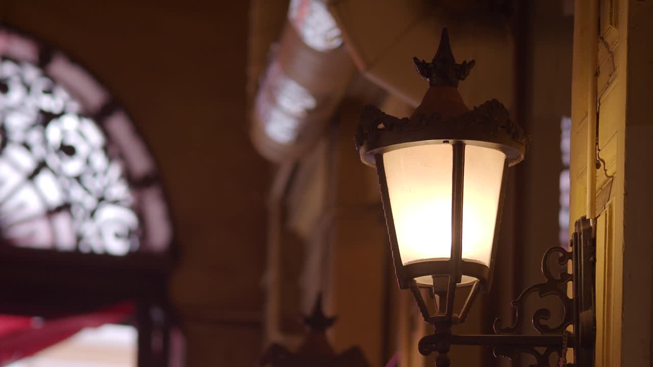 Primo piano di una lampada da parete vintage ornata illuminata di notte.