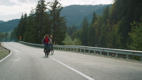 millennials montando bicicletas juntos en el paisaje de las montañas. hipsters en la carretera.