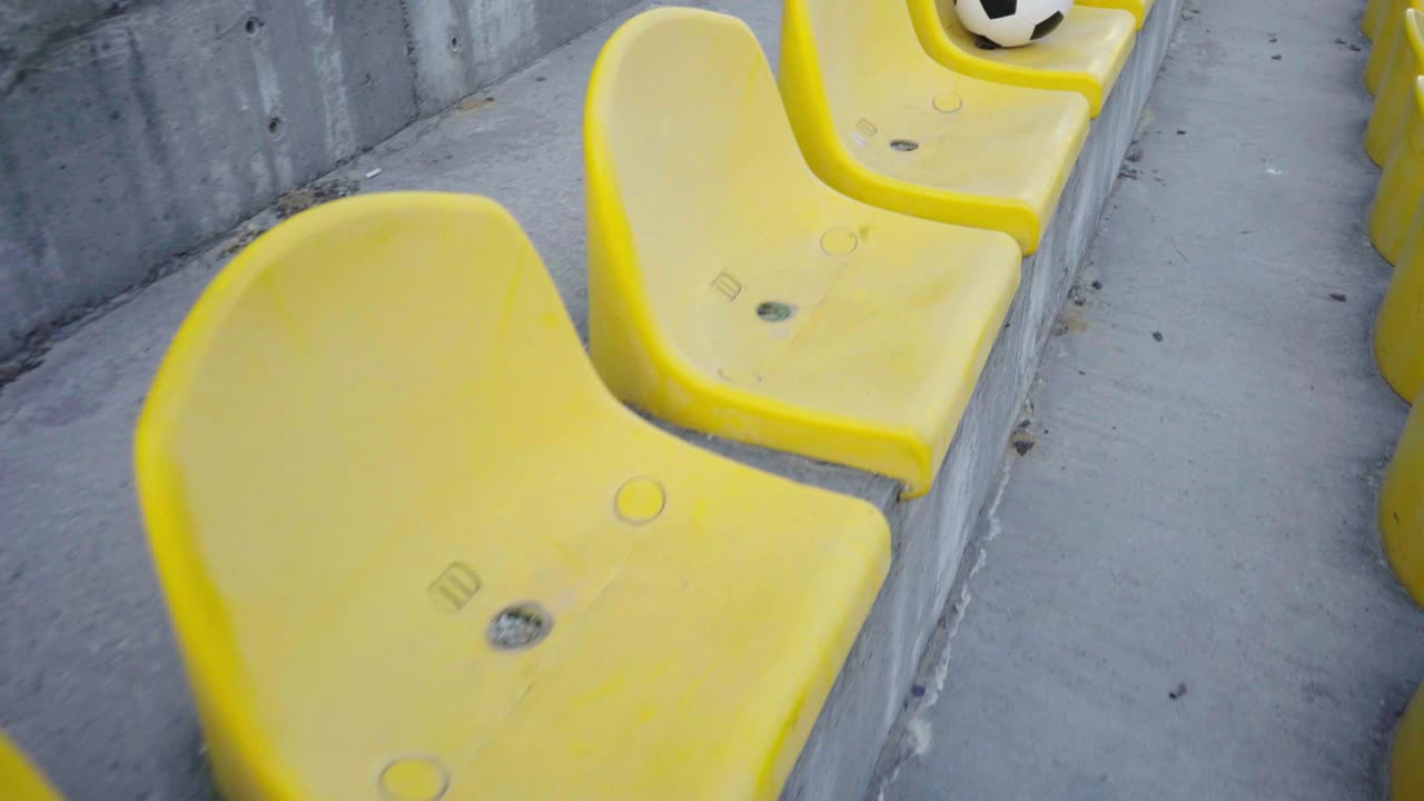 경기장의 포디움에 있는 축구공.  빈 노란 의자