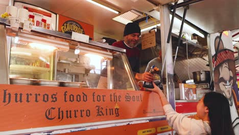 customer purchasing churros from a food stall