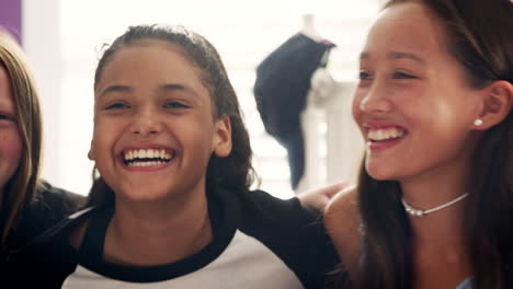 Four-teen-girls-sitting-on-bed-smiling-at-camera,-close-up