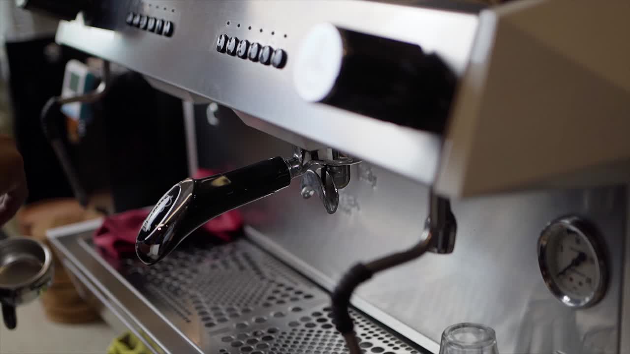 Barista male hands holding portafilter and making fresh aromatic coffee at Cafe using a modern coffee maker in coffee shop