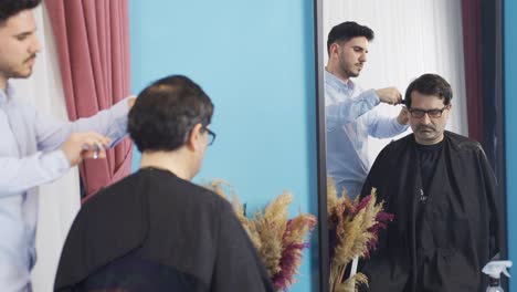 The-boy-is-shaving-his-father's-hair-at-home.-Father-is-grateful-to-his-son.