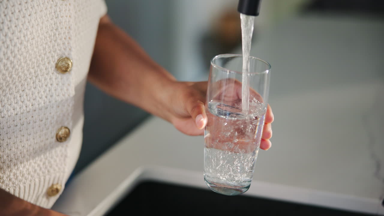 Person's Hands Filling a Glass with Fresh Water from a Tap