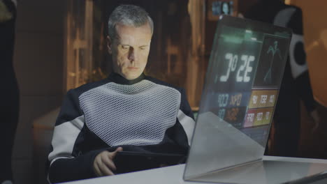 man working on laptop and tablet in futuristic setting