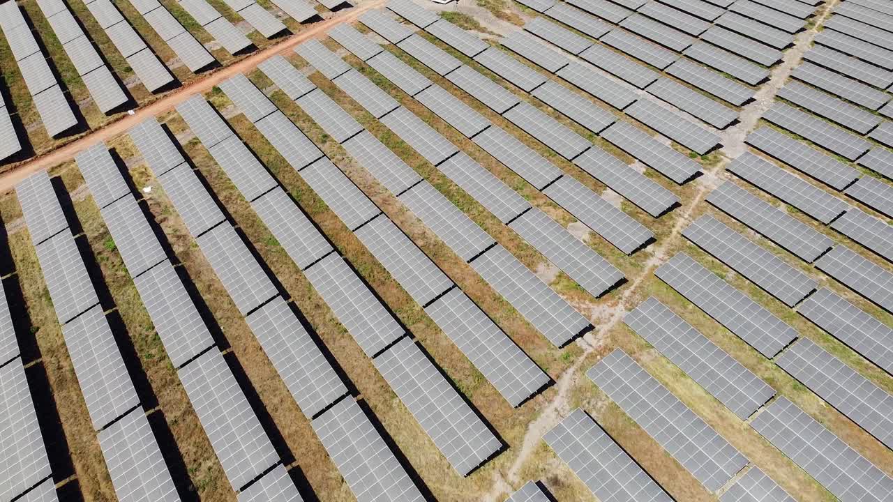 Unique aerial view of renewable energy solar field with visible industrial inverter during sunny day