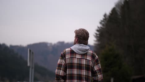 a man dressed in a plaid sweater is shown from behind taking a walk