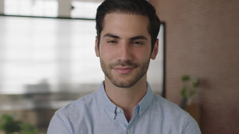 Primer-Plano-Retrato-De-Un-Joven-Y-Atractivo-Hombre-De-Negocios-Del-Medio-Oriente-Mirando-La-Cámara-Sonriendo-Confiado-En-El-Fondo-Del-Espacio-De-Trabajo-De-Oficina