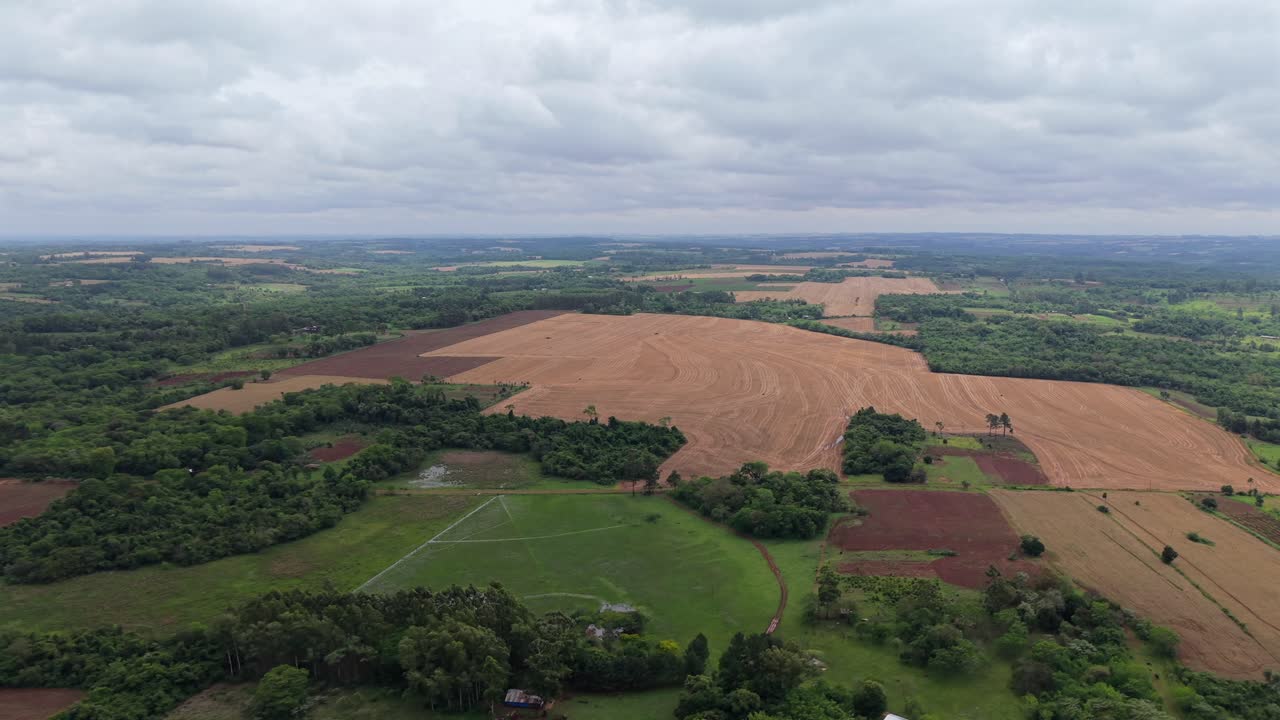 Aerial fly over agricultural fields alternating with green forested patches and plantations, Campichuelo, Paraguay