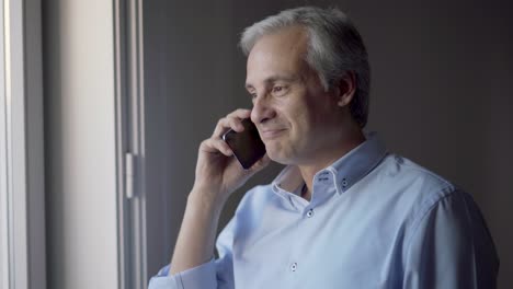 Joyful-middle-aged-man-speaking-on-cell