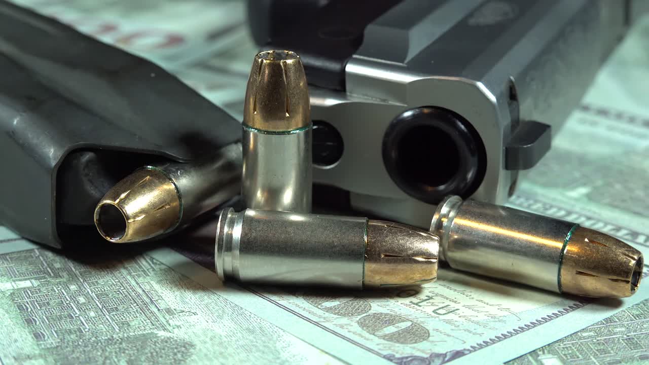 денежный пистолет и пулевые патроны на пачке денег