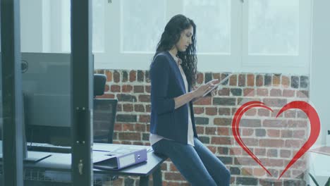icono de corazón rojo contra el retrato de una mujer india usando una tableta digital en la oficina