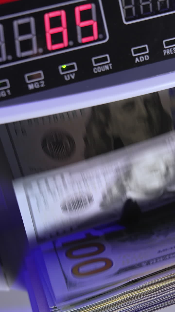 Electronic operations for counting paper money. Cash money counting machine. Banknote counter are counting one hundred dollar bills. Top view. Close-up. Vertical video