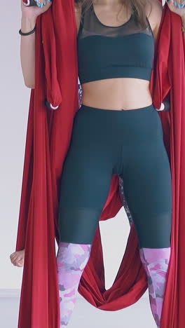 flexible ladies practice oriental fly yoga warrior asana and change legs holding red hammocks close view