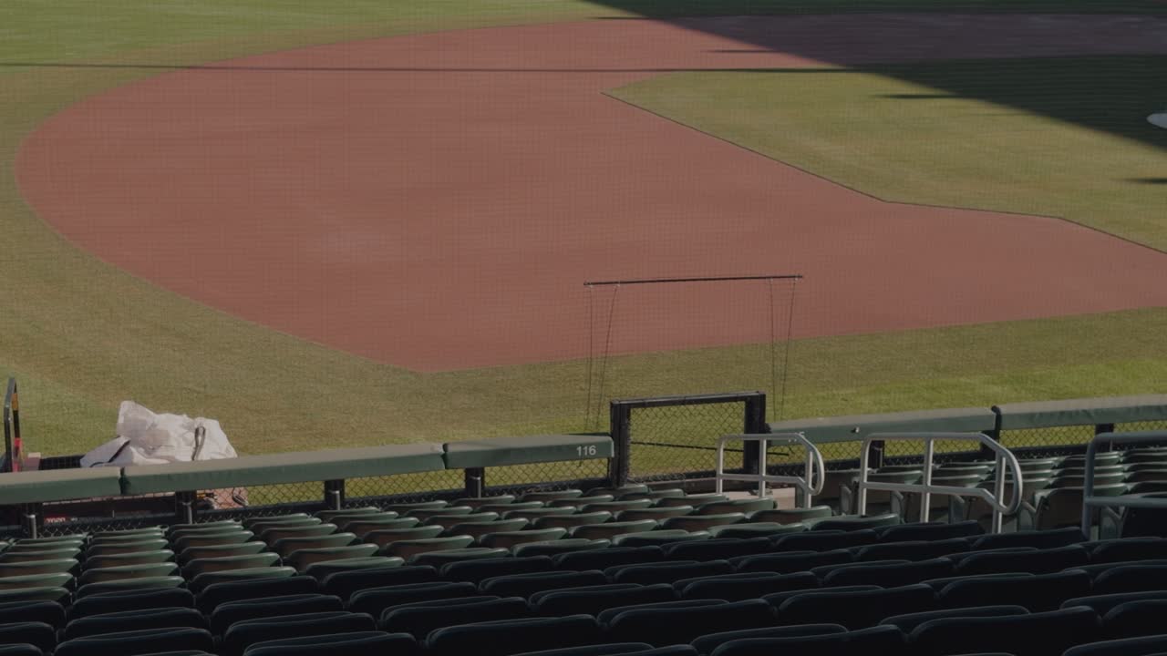 Panoramica lenta e costante da destra a sinistra attraverso gli spalti e il campo interno vuoti di uno stadio di baseball.