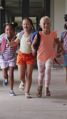 video of happy diverse pupils running on school corridor