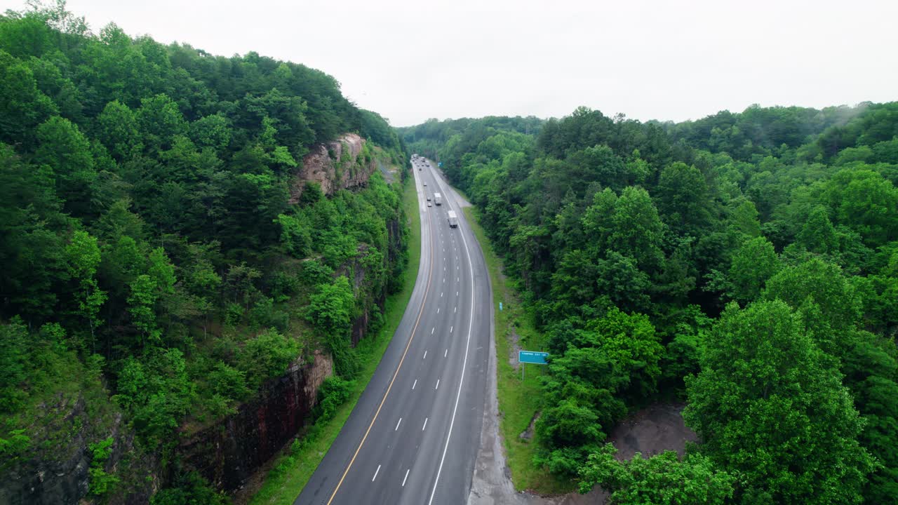 Stationary shot capturing semi trucks hauling cargo along I-24 through Tennessee’s scenic Monteagle Pass.