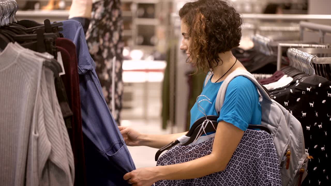 morena no es alta en la tienda. ella recoge otra prenda. preparándose para irse, haciendo compras recientes. ella no estaba de humor, porque no encuentra lo que busca