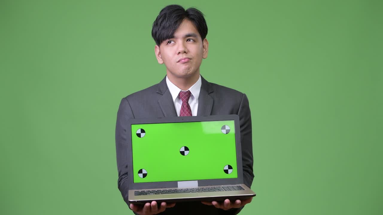 젊은 잘생긴 아시아 사업가 노트북을 보여줍니다.