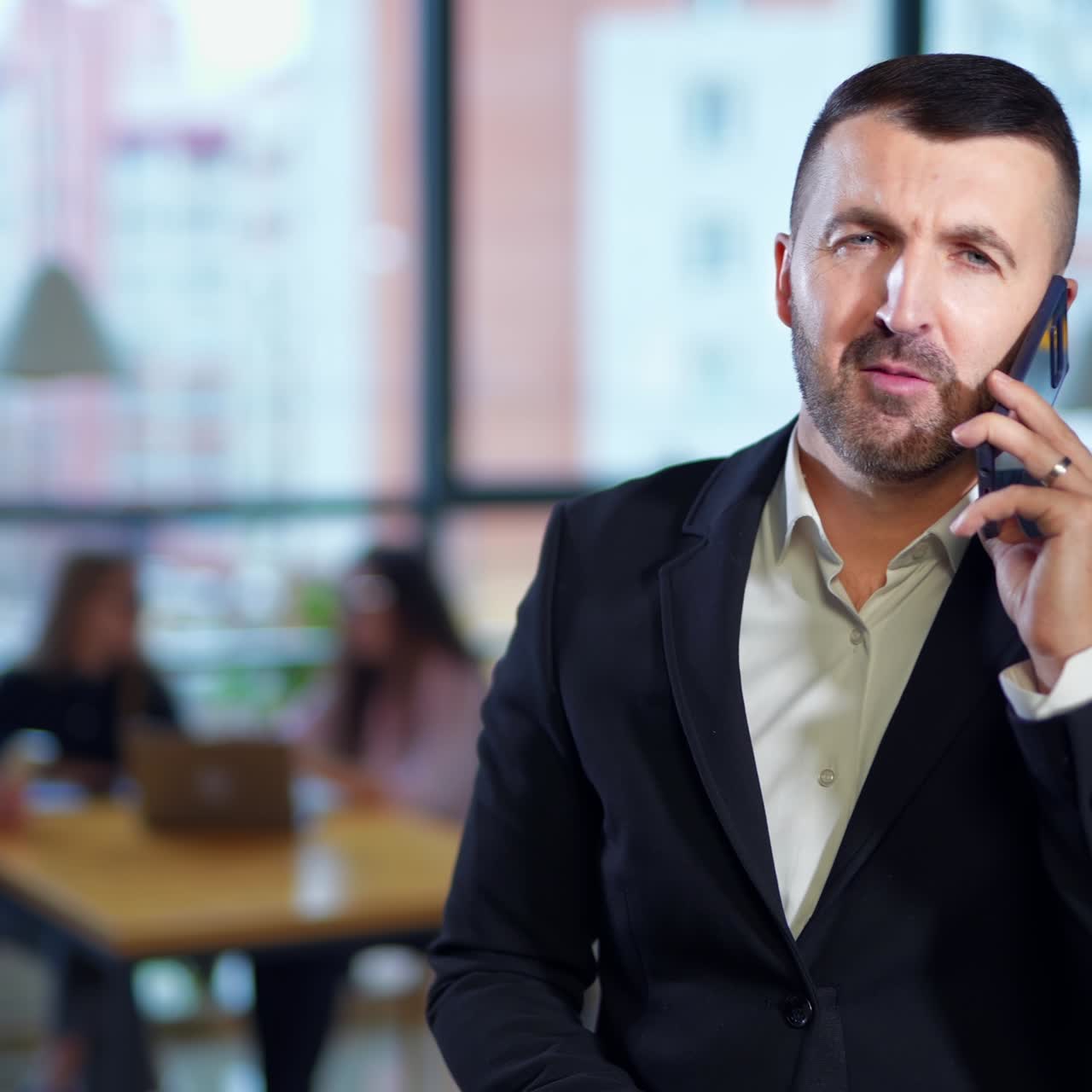 Business talk on the phone in office. Confident businessman speaking on the phone and is very active and lively. Business team sitting at desk and having conversation at backdrop