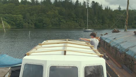 positioning wooden frame over wheelhouse cabin on wooden boat